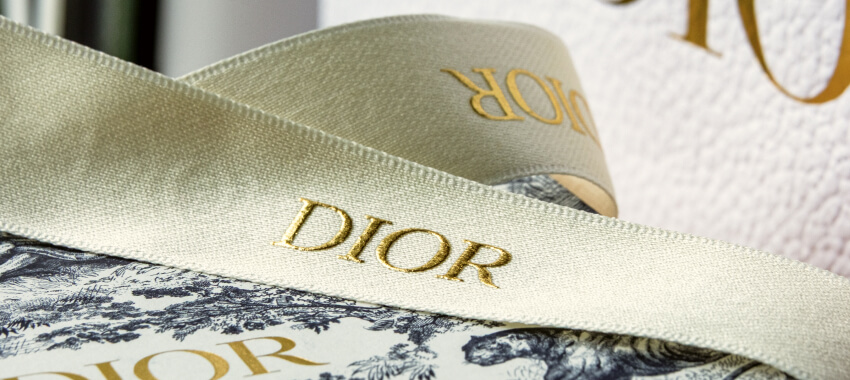 Dior branded ribbons and tissue paper in gold foil lettering on luxury gift packaging