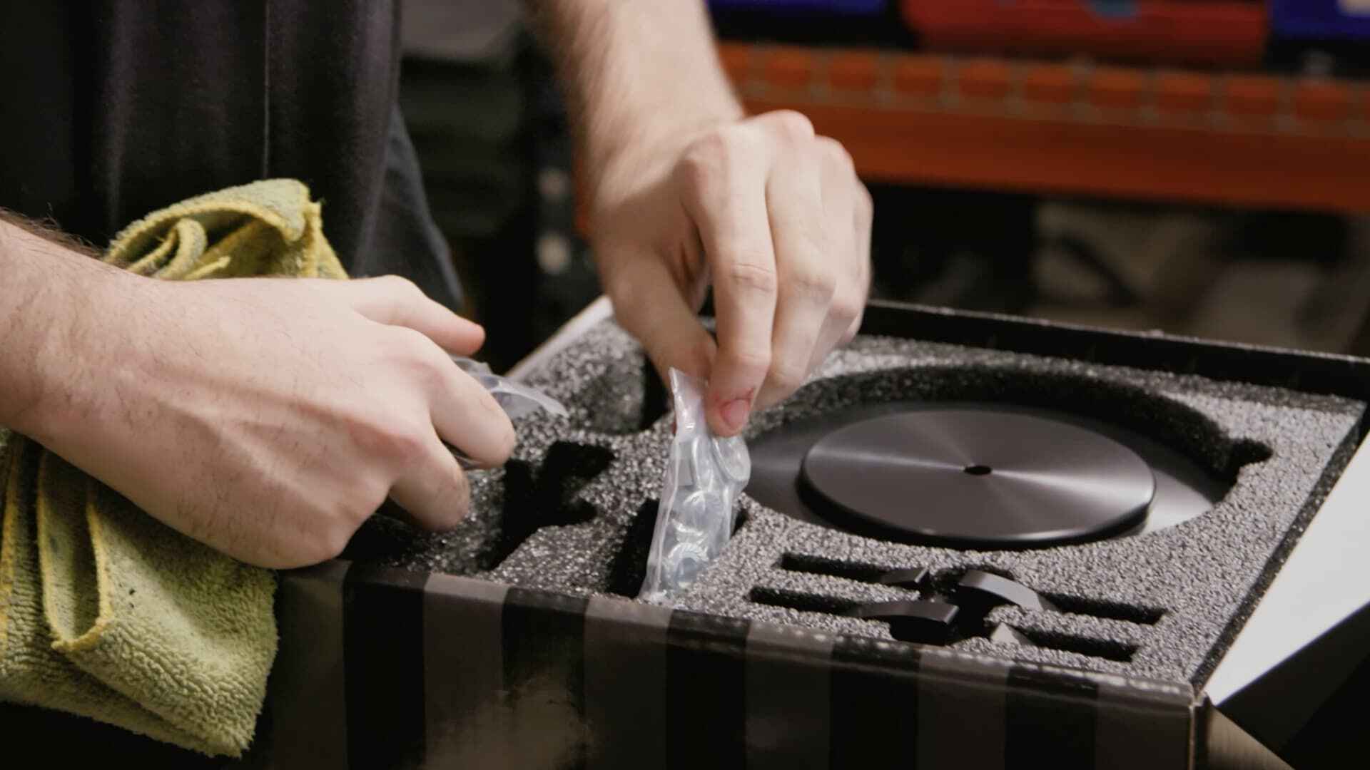 Hands cleaning protective foam padding from industrial equipment using a cleaning cloth